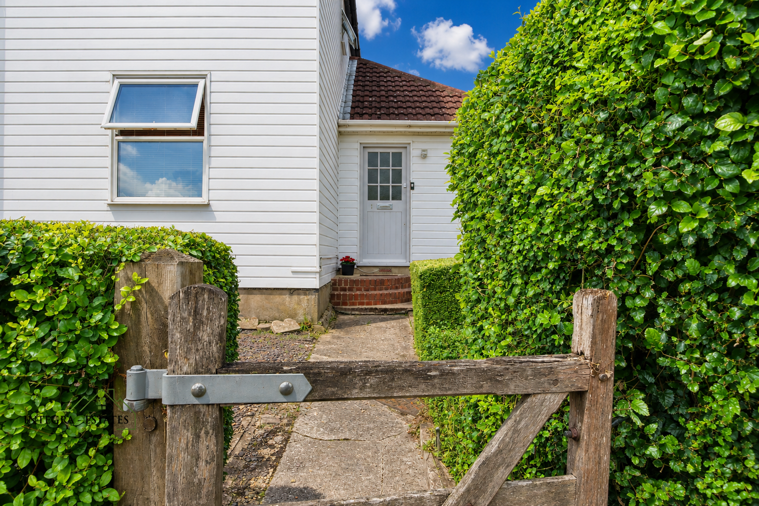 Close up image of a traditional Kent country gate with green hedge and cottage property entrance. its small marketing tweeks that can have a positive difference.