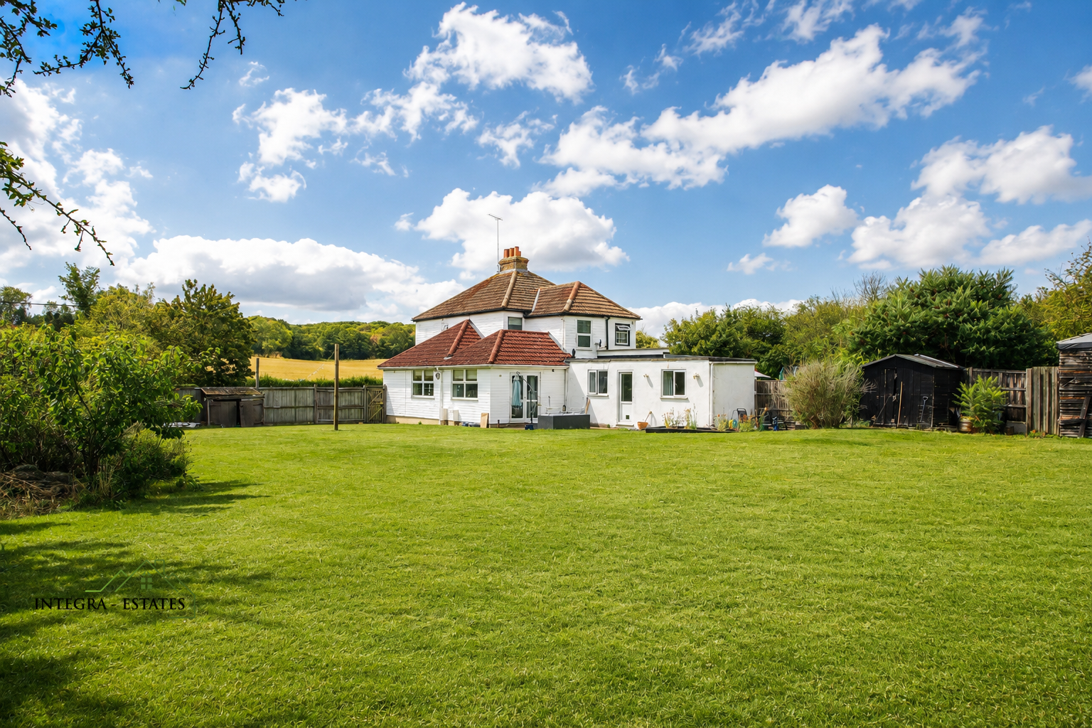 Beautiful property in Valley Road Dartford with expansive outdoor space with a white cottage in the background with glorious blue sky and white fluffy clouds.